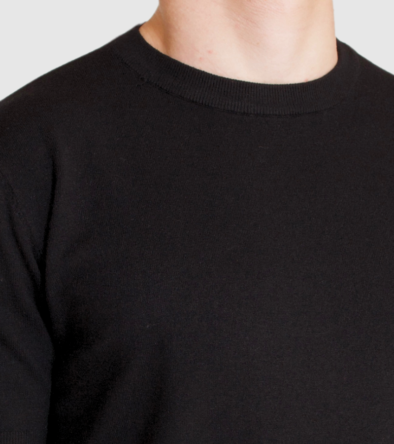 Close-up of a person wearing a black sweater against a light gray background