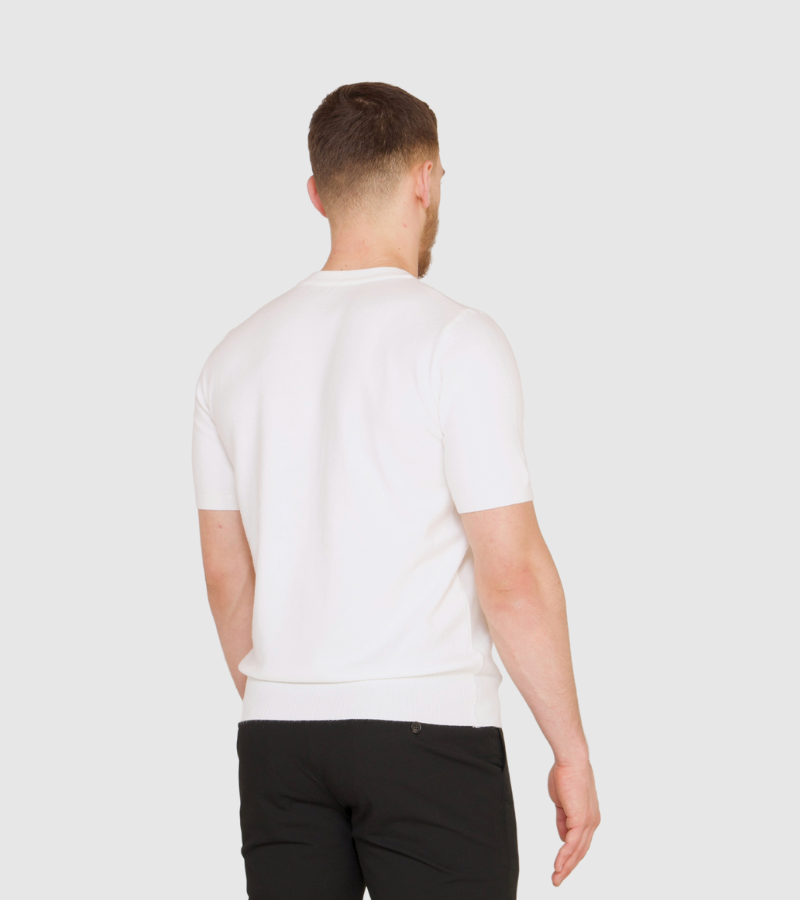 Man wearing a white t-shirt and black pants on a plain background