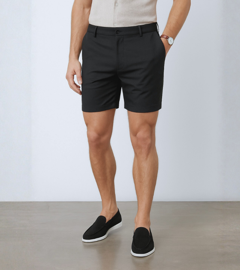 Person wearing black shorts with a plain background